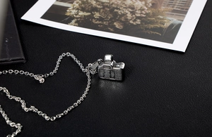 Detail showing high-quality vintage camera pendant necklace on black leather surface