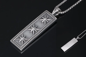 Macro shot of retro silver square pendant with embossed star motifs and beaded borders