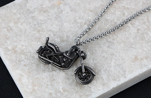 Close-up of a vintage titanium steel motorcycle pendant with a rugged dark grey metallic texture