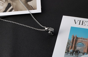 Detailed view of silver camera pendant necklace on black leather and photo cards