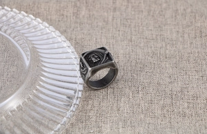 Gros plan détaillé d'une bague faucheuse rétro avec faux sur fond gris texturé