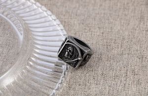 Détail d'une bague tête de mort et faucheuse vintage sur une surface en tissu texturé