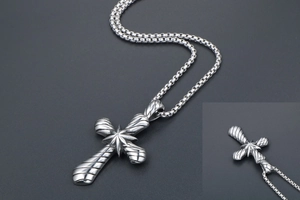 Détail du pendentif croix rétro en acier titane avec texture spirale et chaîne box