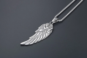 Vue macro d'un pendentif aile en plume argentée avec rose sur une chaîne vénitienne