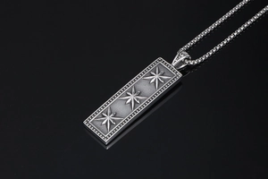 Macro view of vintage rectangular pendant with relief star patterns and box chain link