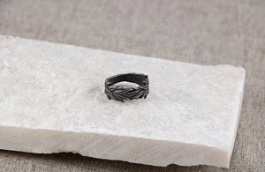 Detailed view of vintage oxidized steel ring with wheat leaf pattern on stone texture