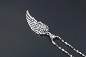 Vue macro d'un collier plume argenté avec pendentif rose et aile d'ange sur chaîne