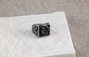 Détail macro du relief de faucheuse gothique et crâne ailé sur bague en argent rétro