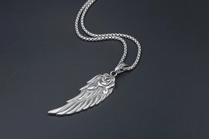 Détail macro du pendentif aile de plume avec gravure de rose sur une chaîne épaisse