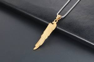 Detailaufnahme eines goldenen Flügelanhängers mit silberner Stahlkette auf Leder
