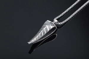 Macro detail of silver antelope horn pendant with geometric V-shaped textures and box chain