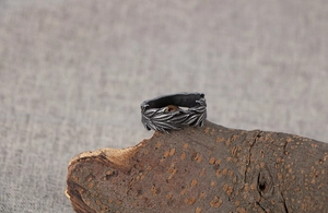 Detailed view of vintage silver ring with leaf patterns on a natural wood block