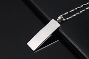 Macro detail of silver rectangular pendant with brushed finish and textured link