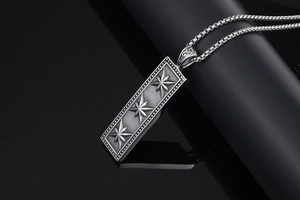 Macro shot of vintage rectangular pendant featuring embossed stars on a black reflective surface