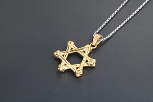 Dettaglio del ciondolo a esagramma dorato con trama a osso su una collana a catena