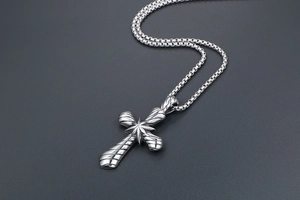 Macro d'un pendentif croix vintage en acier titane avec texture torsadée et détail étoile