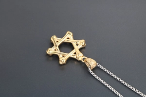 Dettaglio di un pendente esagonale dorato a forma di osso con catena box argento