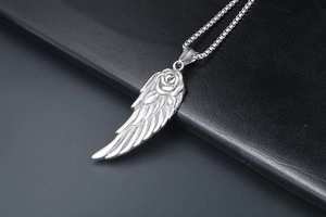 Vue détaillée du pendentif aile d'ange et rose en argent sur une chaîne à mailles
