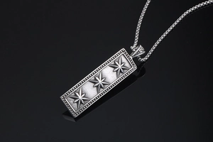Macro detail of square stainless steel pendant with embossed eight-pointed stars