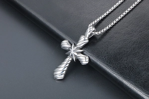 Vue macro d'un pendentif croix en acier titane avec relief d'étoile sur cuir noir
