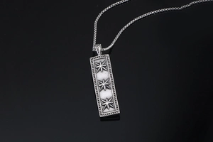 Macro shot of rectangular silver pendant featuring three engraved eight-pointed stars