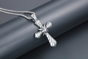 Détail du pendentif croix en acier titane avec texture torsadée et motif étoilé