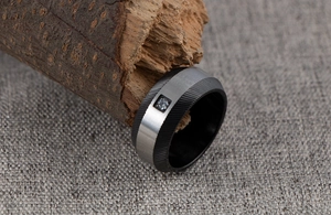 Macro detail of men's two-tone stainless steel ring with blue zircon inlay on wood