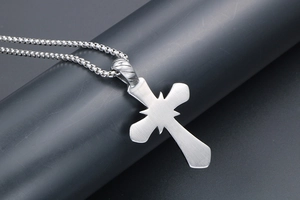 Détail du pendentif croix en acier argenté avec gravure d'étoile et chaîne maille box