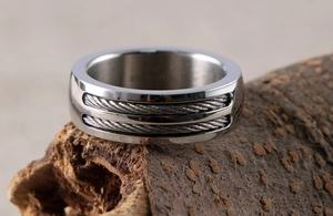 Macro shot of men's industrial stainless steel ring with double cable inlay and engraving