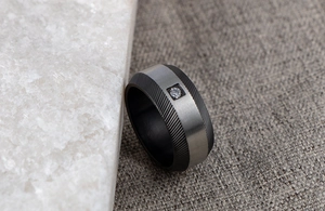 Detail of men's wide stainless steel ring with black grooves and a single CZ stone
