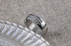 Detail of men's wide stainless steel ring with three steel cable textures on gray fabric
