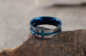Macro view of stainless steel ring with blue cross detail on textured tree bark