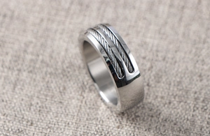 Macro detail of men's stainless steel ring featuring dual steel wire cable inlays