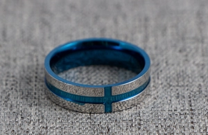 Close-up of silver and blue stainless steel ring featuring a cross bottle opener design