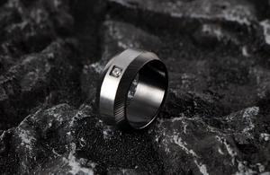 Macro detail of men's wide stainless steel ring with brushed silver finish and black grooves