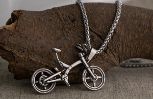 Detailed close-up of retro bicycle pendant in oxidized titanium steel on a box chain