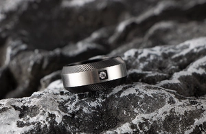 Macro shot of men's black and silver textured ring with a cubic zirconia on rock