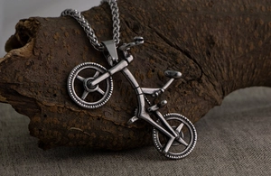 Macro detail of retro industrial titanium steel bicycle pendant on a natural bark texture