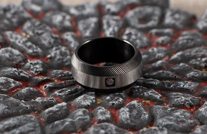 Macro shot of men's two-tone steel ring with sandblasted stripes and a single diamond inlay