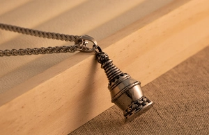 Close-up of vintage titanium steel stupa pendant with detailed lotus base and rope chain