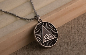 Gros plan du collier vintage en acier titane avec pendentif œil sur support bois