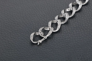 Makro-Detail eines Vintage-Gothic-Titanstahl-Armbandes mit graviertem S-Muster auf Leder