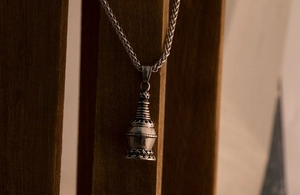 Close-up of vintage titanium steel stupa pendant with detailed lotus base carving