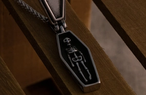 Macro shot of opening coffin pendant with a skeleton inside on a rustic wood background