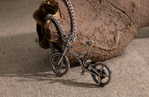 Detail of vintage bicycle pendant necklace on wood with realistic frame and spoke wheels