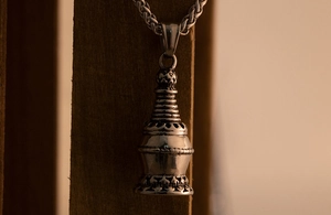 Macro view of vintage titanium steel stupa pendant with detailed lotus base carving