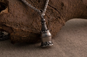 Detail of vintage silver pagoda pendant with lotus base on rustic wood background