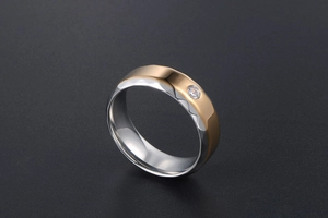Gros plan d'une bague en titane bicolore avec facettes géométriques et zircone