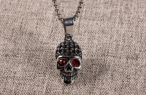 Detailed close-up of a silver skull pendant with red rhinestone eyes on a chain