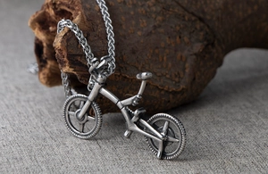 Detailed close-up of a vintage bicycle pendant on a rustic wood bark background